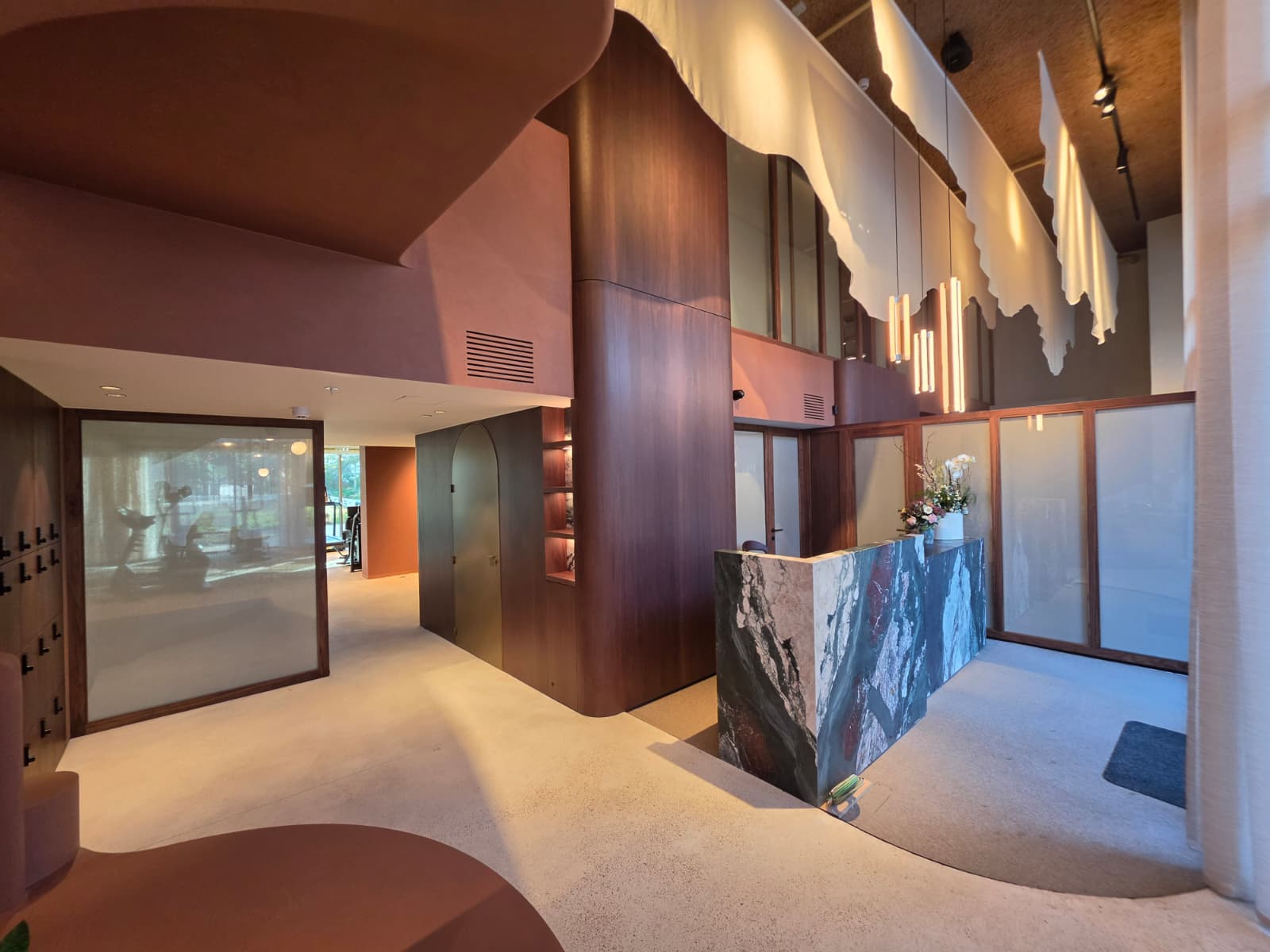 Bonsai reception — walnut and marble front desk beneath sculptural pendant lighting